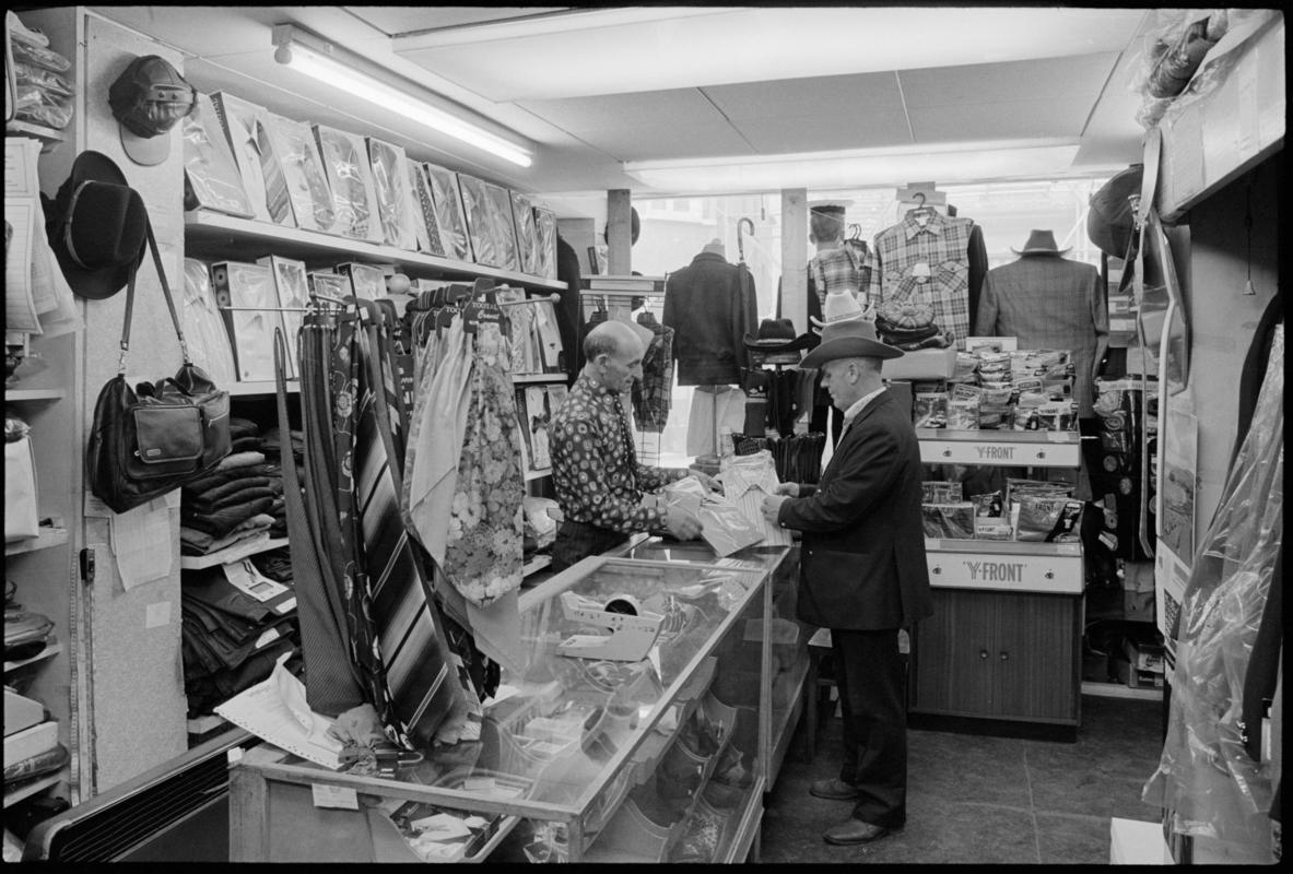 Interior view of &#039;Maurice Merchant Navy General Outfitter&#039;, 5 James Street, Butetown, showing the proprietor Mr M. Colpstein serving merchant seaman Mr T. Szarota. This was the last remaining outfitters in Cardiff Dockland.