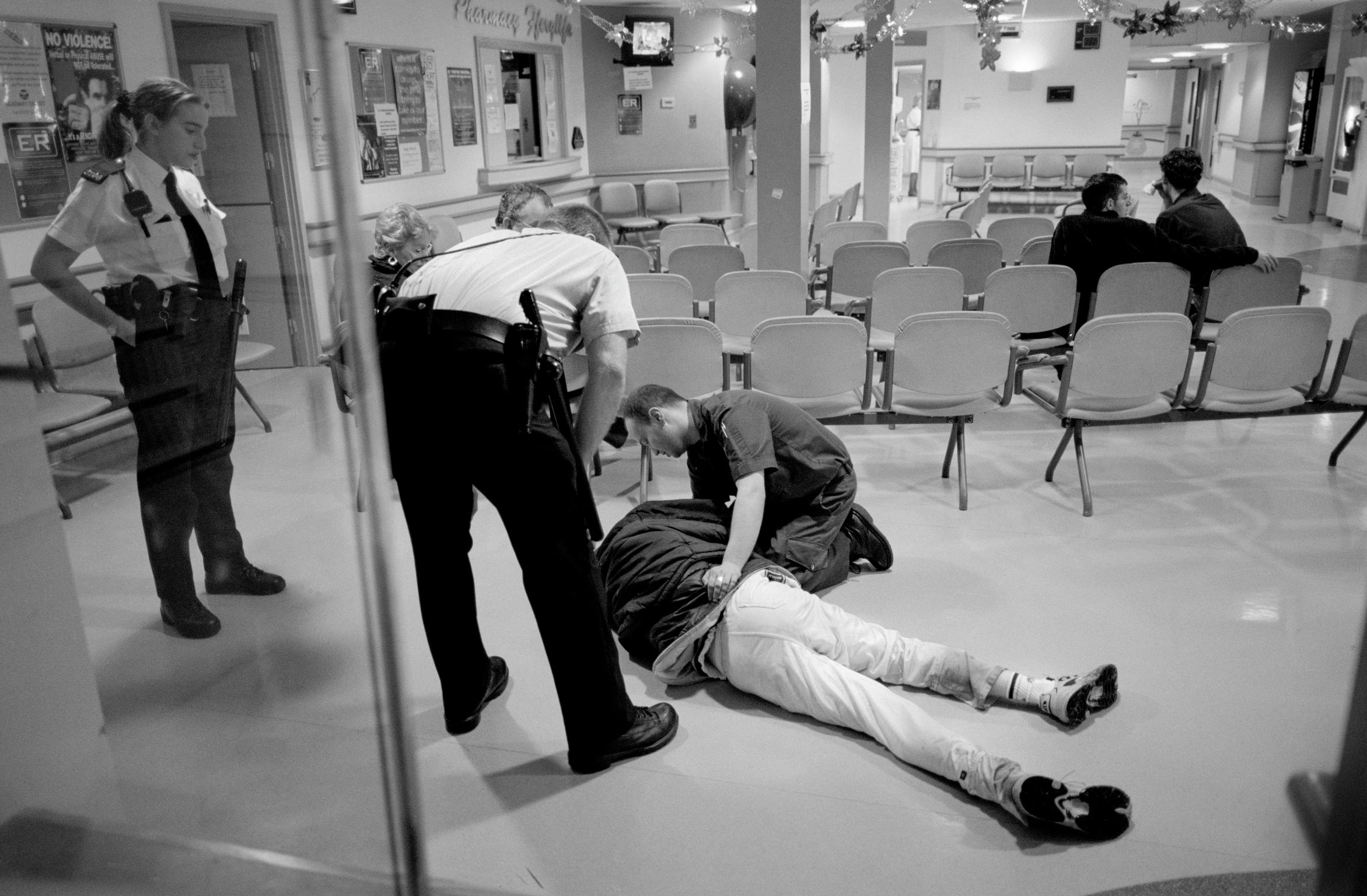 Emergency accident area, University Hospital. A violent patient, very much the worse for drink, collapses in the waiting area and the police are called. Cardiff, Wales