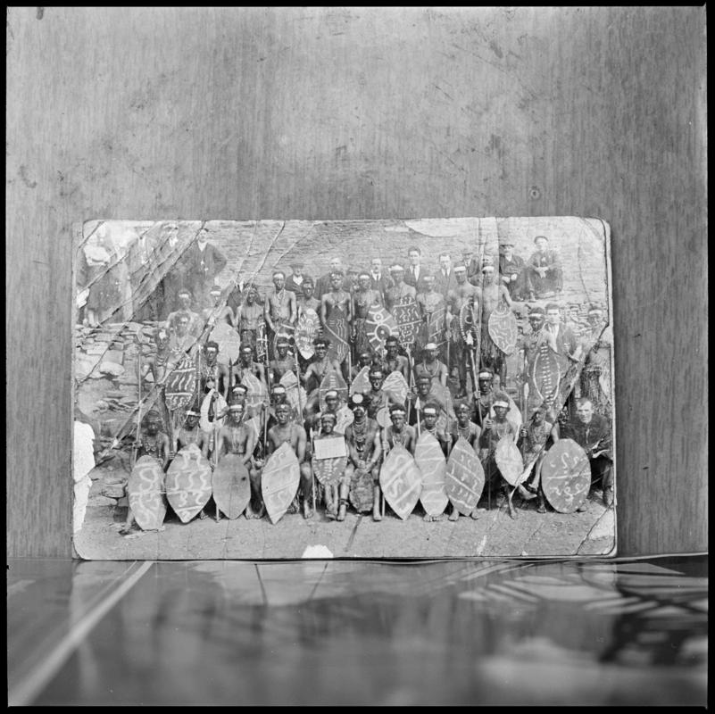 Black and white film negative showing a photograph of a group of men with shields.