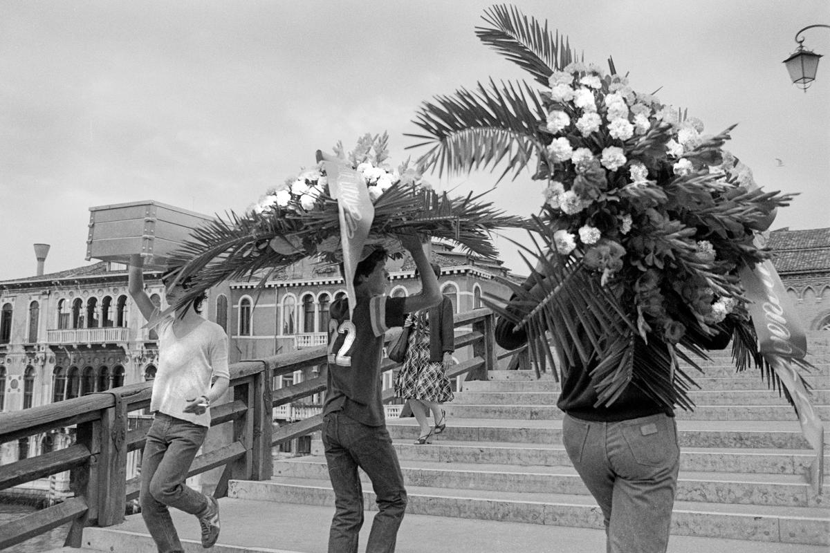 ITALY. Venice. Hand delivery of funeral flowers, youths crossing one of the many bridges in Venice. 1999.