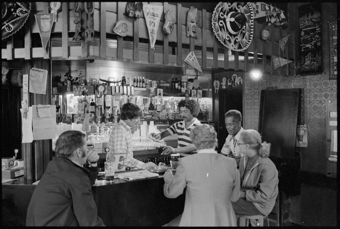 Interior view of the Ship &amp; Pilot public house showing people drinking at the bar, Mount Stuart Square, Butetown.