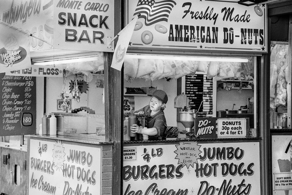 GB. WALES. Rhyl. Snack bar, ice-cream and burgers, American doughnuts. Evening. 1997.