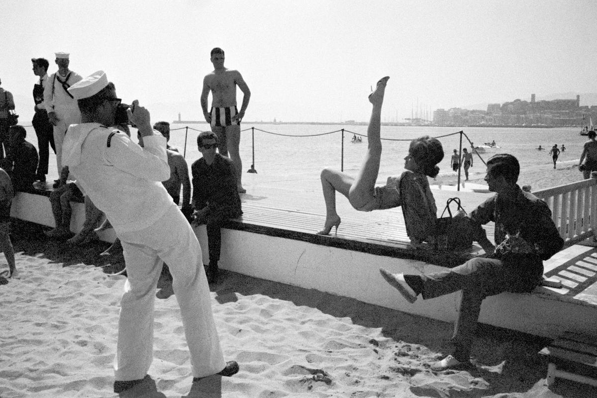 FRANCE. Cannes. Minor star poses on the beach at the Cannes Film Festival. An American ship had arrived in the bay and the sailors were on shore leave. 1964.