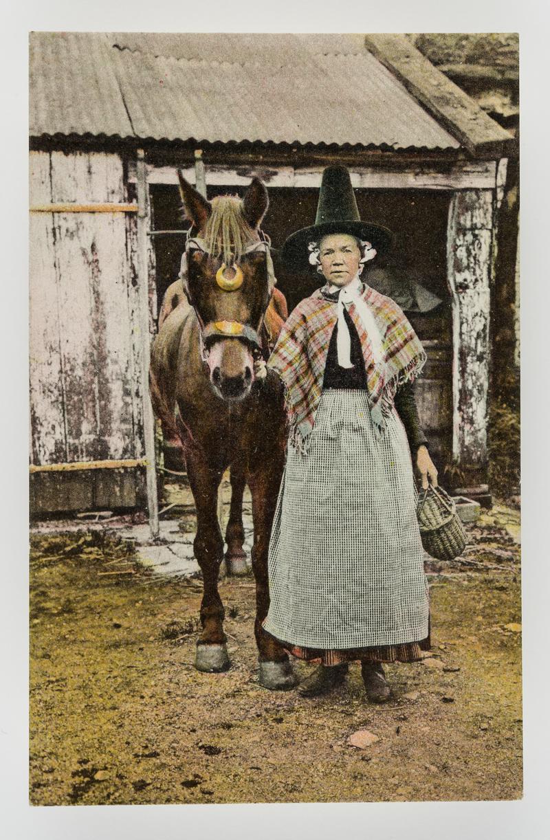 Woman in Welsh costume leading a horse.