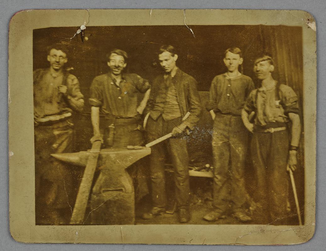 Five workers in a colliery blacksmith shop.