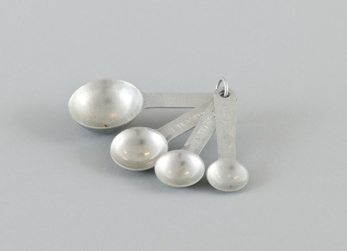 Set of 4 aluminium measuring spoons held together with aluminium ring. Measuring tablespoon, teaspoon, half teaspoon and quarter teaspoon.