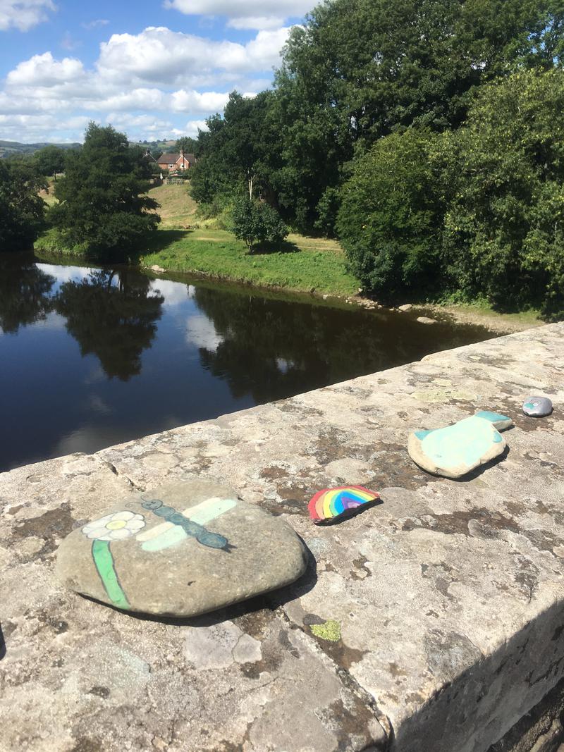 A line of painted pebbles on Boughrood Bridge, over the River Wye, Boughrood, Powys.