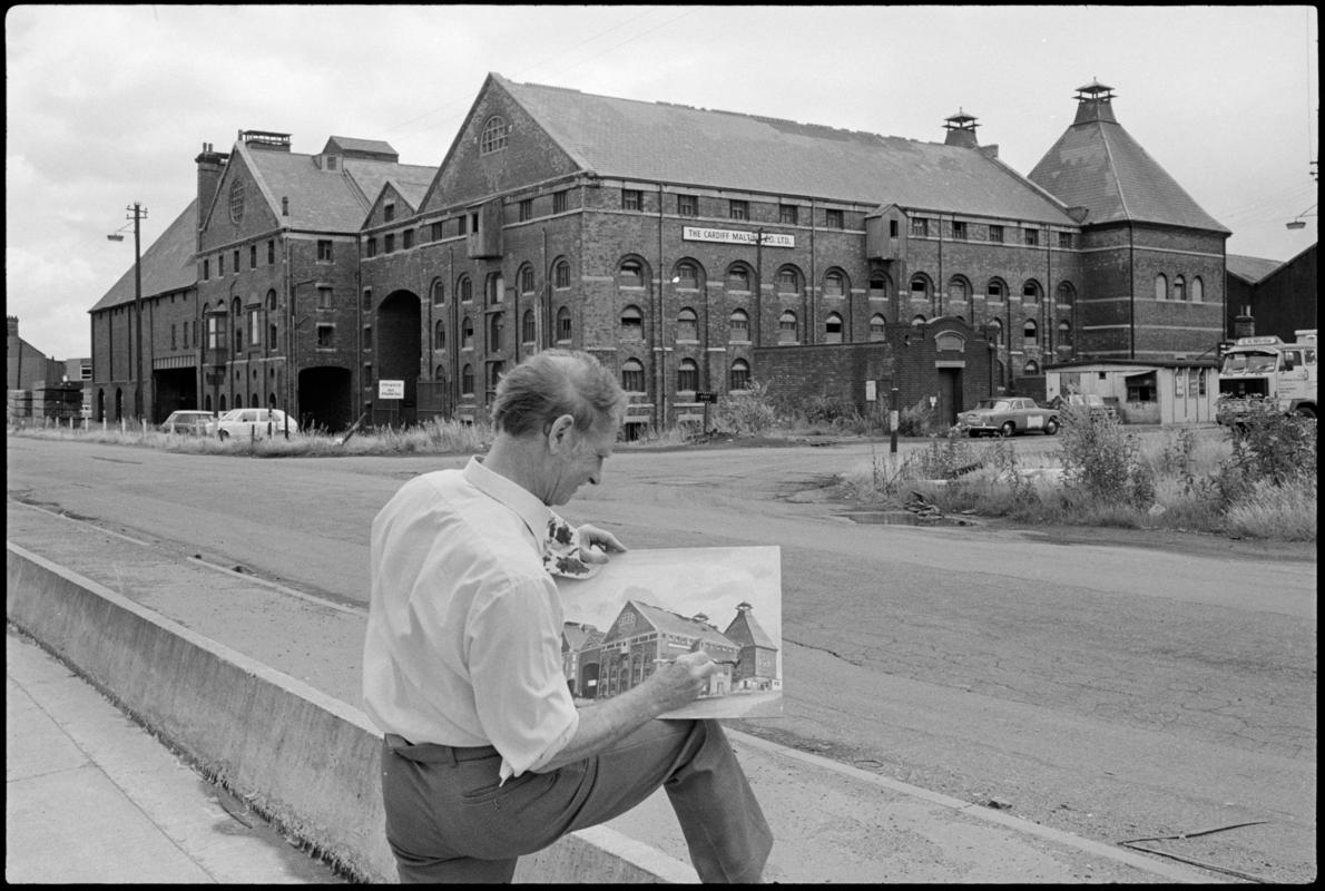 The buildings of the Cardiff Malting Co. Ltd with Mr C. Stevens painting a picture in the foreground.