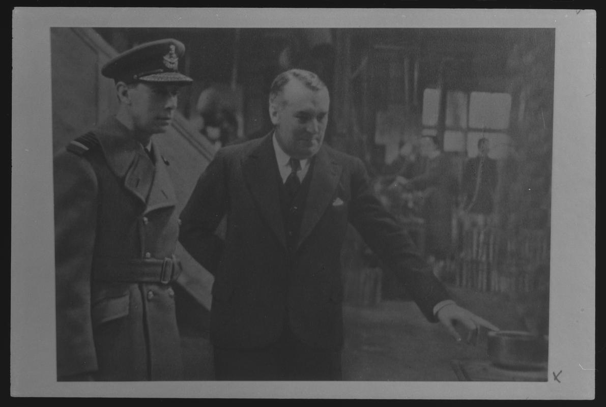 Film negative of a photograph showing visit of King George VI and Queen Elizabeth to Currans, Butetown during World War II. King George VI is with Mr Curran.