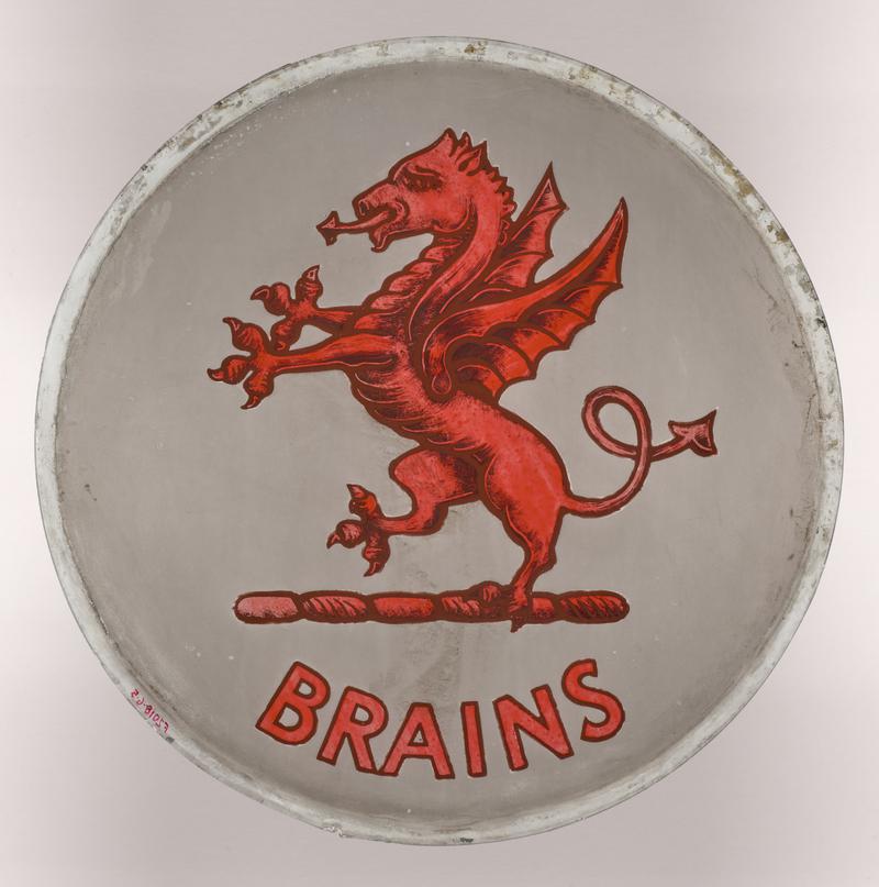 Enamelled roundel depicting the Red Dragon logo of Brains Brewery, Cardiff. Last one of an original set of four that formed part of the leaded windows of The Vulcan Hotel. Likely installed after 1956.