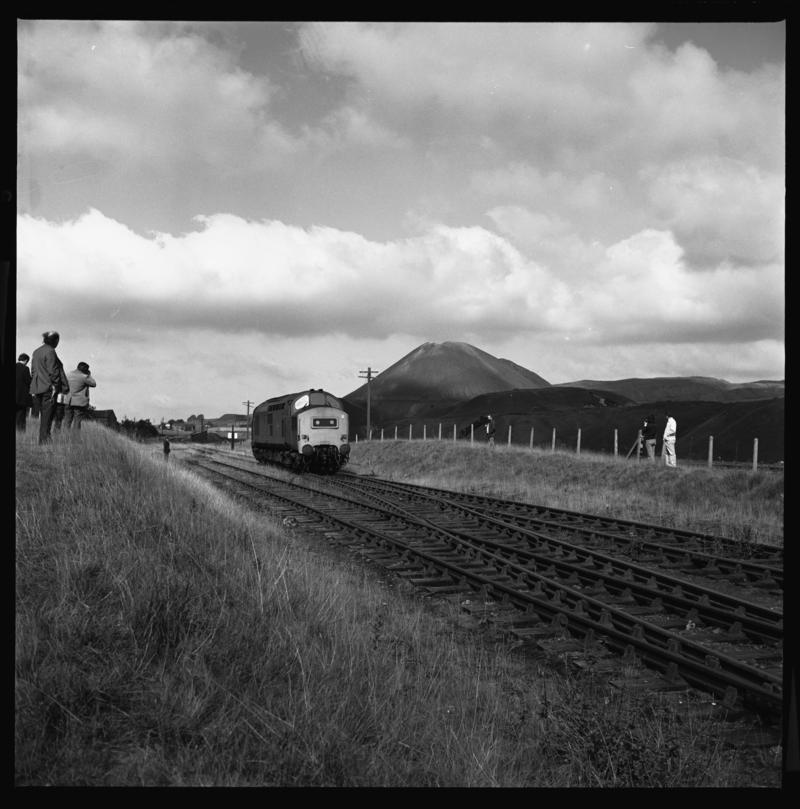 Black and white film negative showing a locomotive in Blaenavon with the Garn tips in the background.
