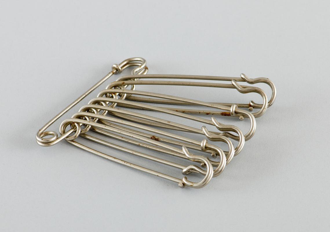 Eight &#039;nappy&#039; pins attached together.