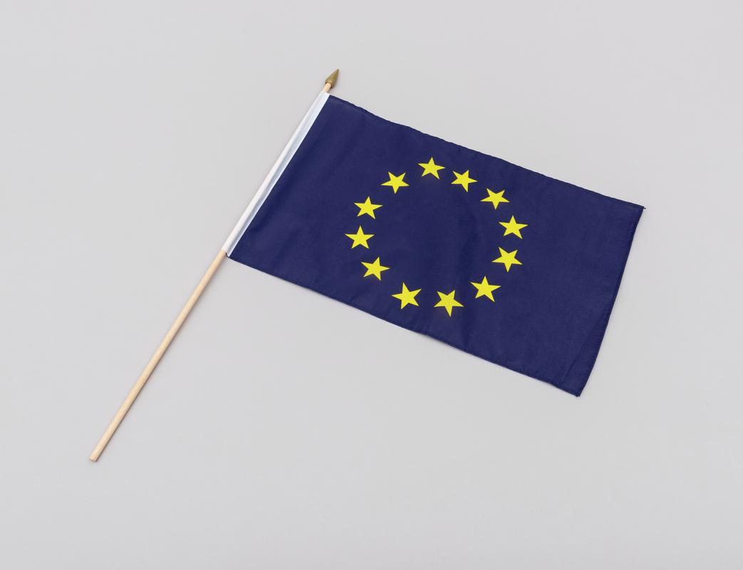 European Union hand flag (12 gold stars on a dark blue background) with a wooden stick.
