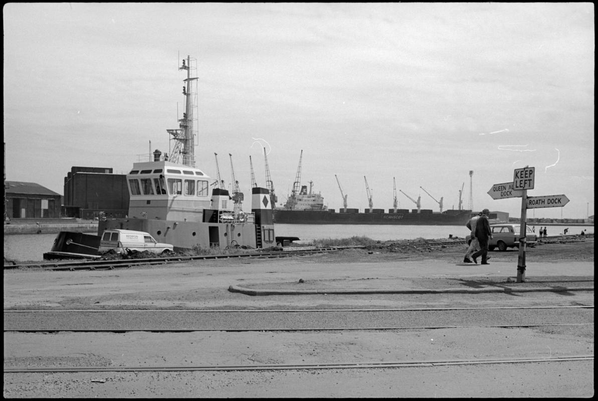 View of tug, large vessel and signpost to Queen Alexandra Dock and Roath Dock.