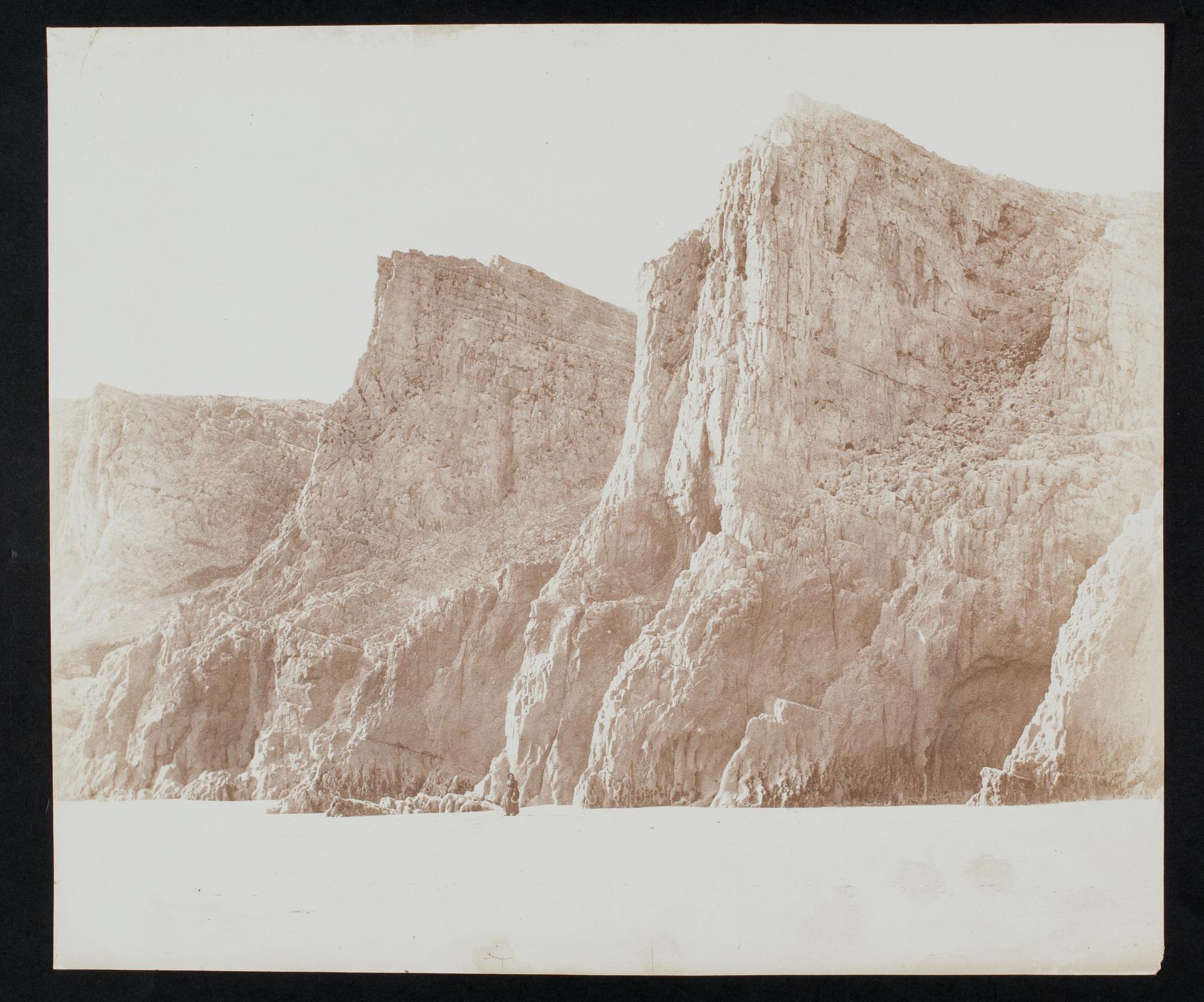 Beach with cliffs and female figure, photograph