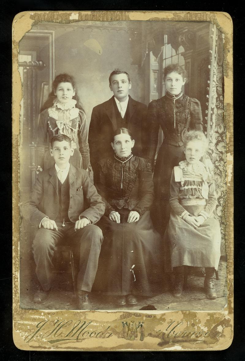 Studio photograph (cabinet print size) of the family of John Pippin. 
From left to right back row - Sarah, Robert John and ?
From left to right front row - Rhys, Mary Pippin (widow of John) and Lizzy
