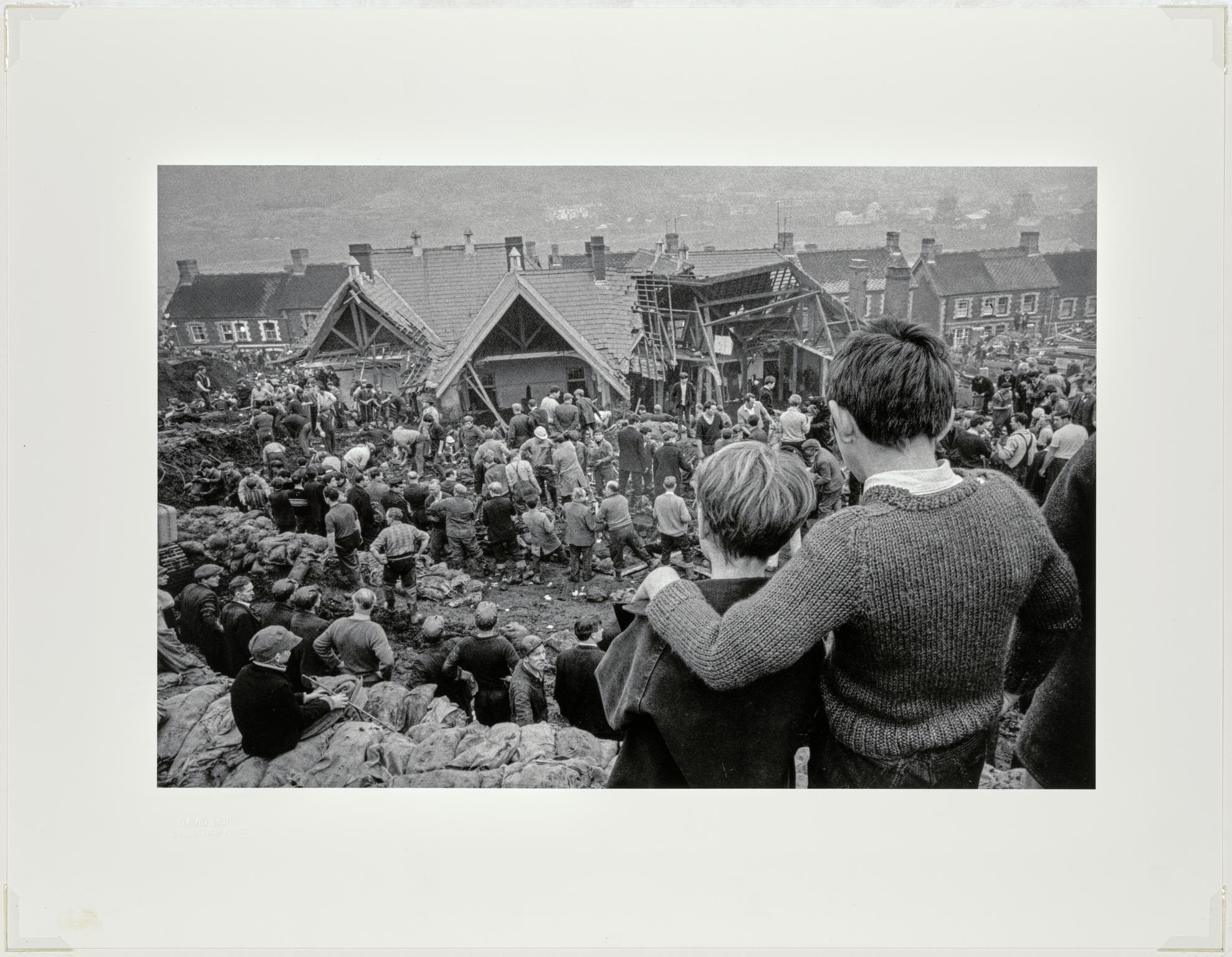Aberfan Coal Slip Disaster. Two surviving children stand at the top of the hill overlooking the miners digging to find children still buried in the slag