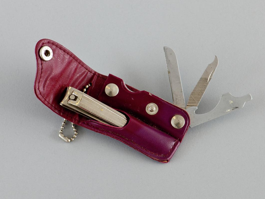 Manicure set comprising removable metal nail clippers and separate retractable metal file and knife, in purple plastic case with ring for attachment.