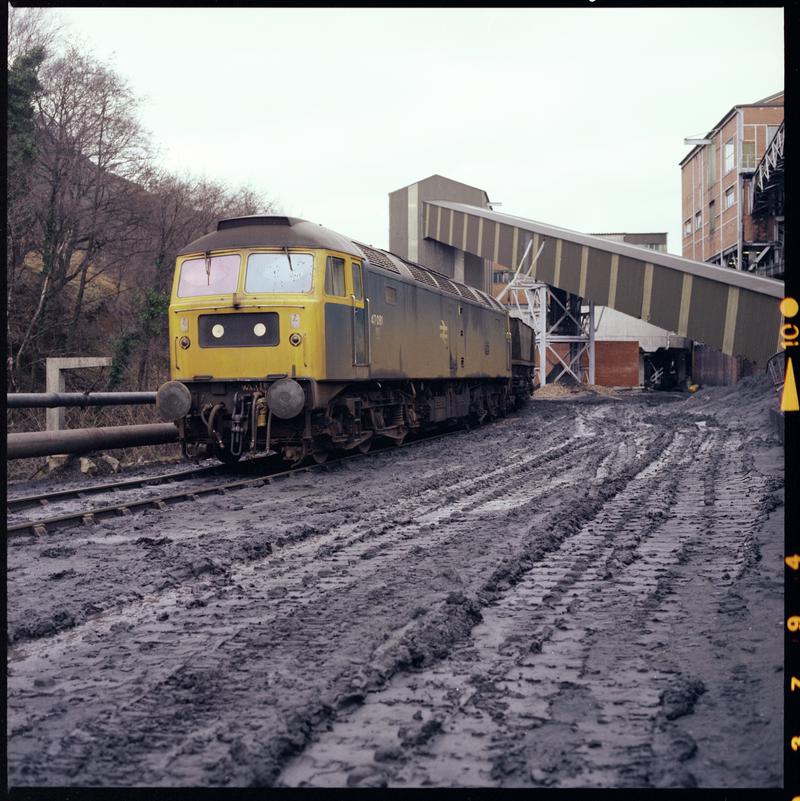 Colour film negative showing a locomotive passing through Taff Merthyr Colliery 1970s.