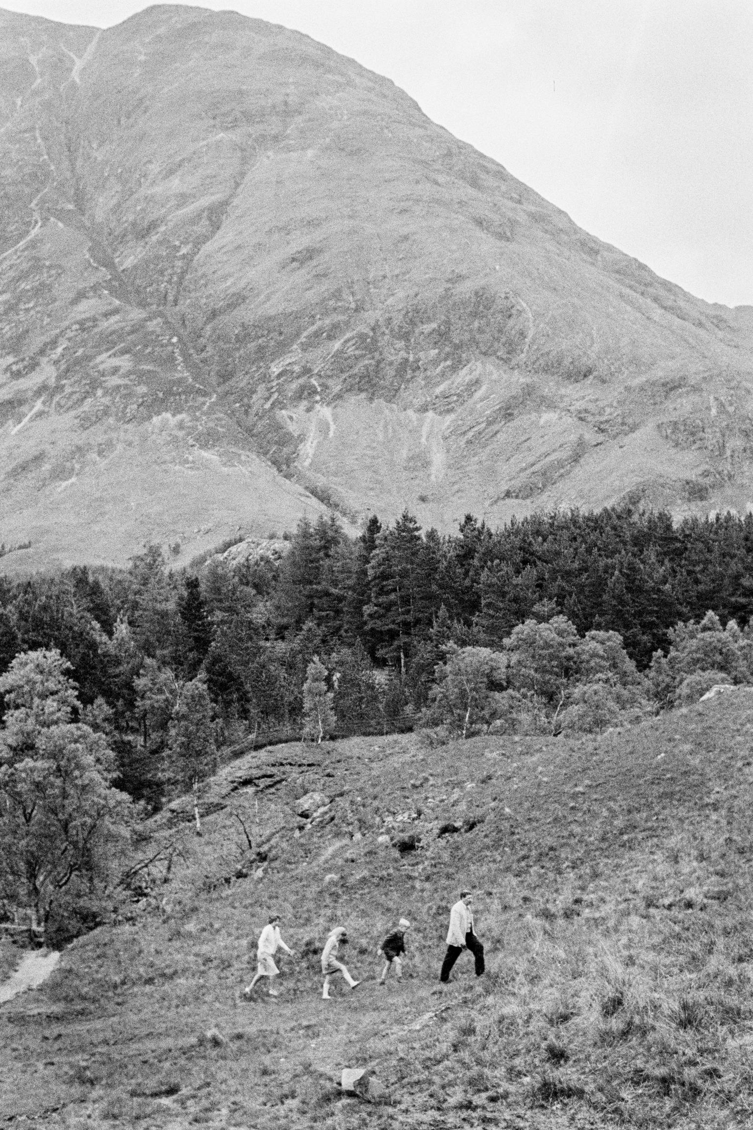 A family group walk across the hill-side with the Mountain Ben Nevis. Scotland