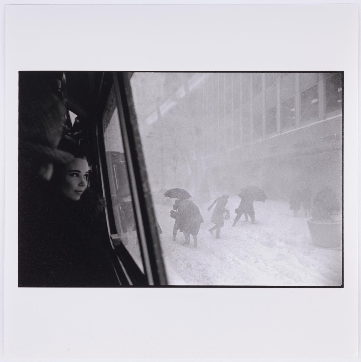 Girl in bus and figures in street during snowstorm, New York City