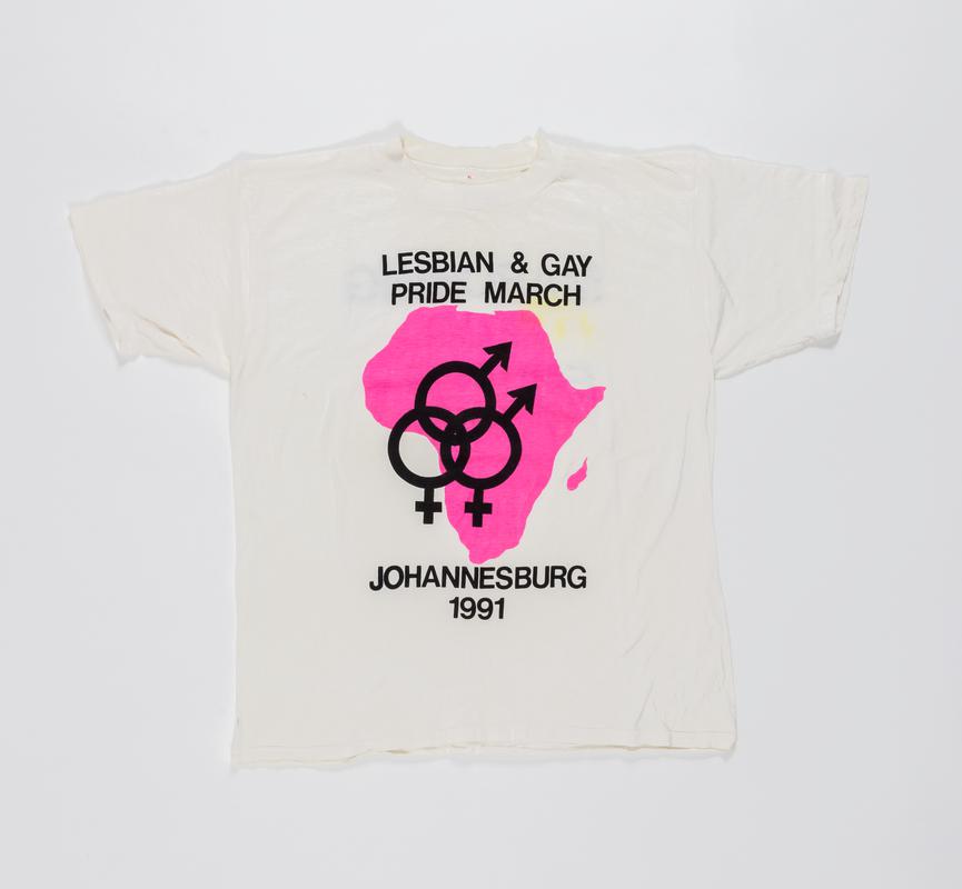 White t-shirt with double womens symbol within a pink outline of Africa, and words &#039;Lesbian &amp; Gay Pride March Johannesburg 1991&#039; on the front, and &#039;Marching for Equality&#039; on the back.