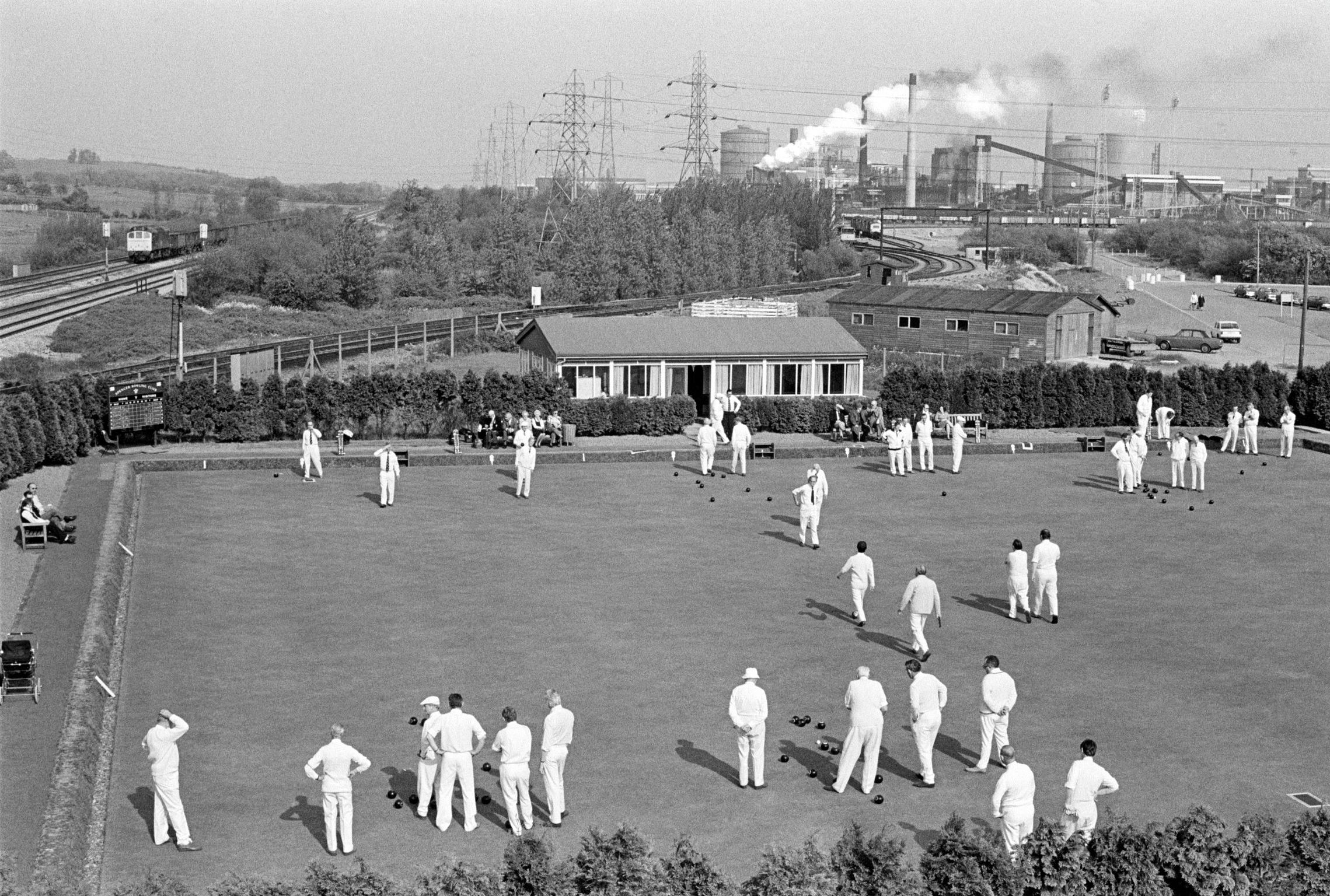 The contrast between the healthy activity of Newport Bowling Club, all wearing their whites battling the dirt and pollution of Llanwern steel works in the background. Newport, Wales