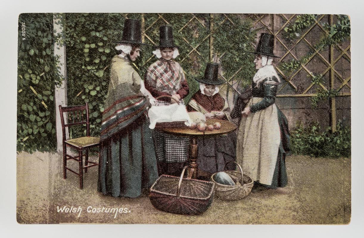 4 women in Welsh costume around table, with baskets of garden produce.