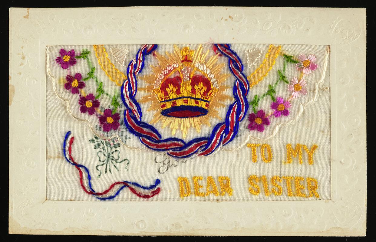 Embroidered silk postcard inscribed To My Dear Sister. Sent from France possibly by Gordon Hobbs to his sister Hilda during First World War. Undated. Embroidered with red and gold crown, red, white and blue rope, and red flowers. Flap opening contains a card printed Good Luck. No message on back.