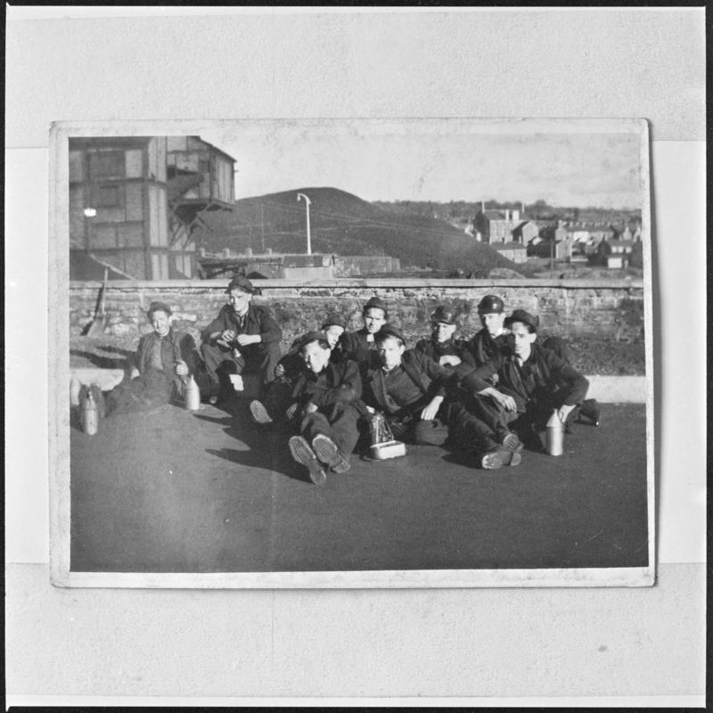 Black and white film negative of a photograph showing a group of miners sat on the ground, Deep Navigation Colliery.  &#039;Deep Navigation&#039; is transcribed from original negative bag.