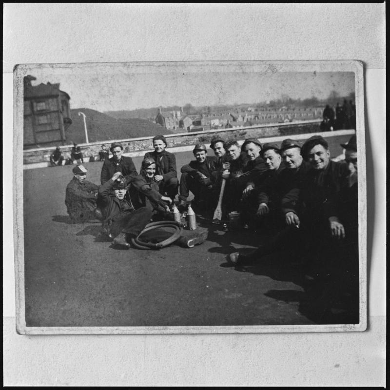 Black and white film negative of a photograph showing a group of miners sat on the ground at Deep Navigation Colliery.  &#039;Deep Navigation&#039; is transcribed from original negative bag.