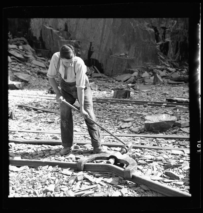 Quarryman straightening a section of rail, using a &#039;Jim Cro&#039;, Dinorwig Quarry, early 1960s.