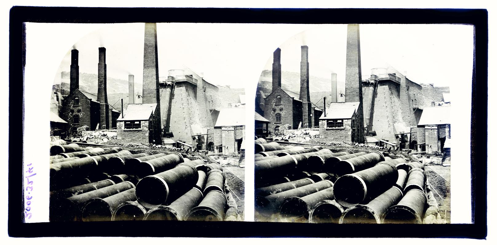 Glass stereoscopic slide showing stacks of pipes with a blast furnace in the background, Brymbo.