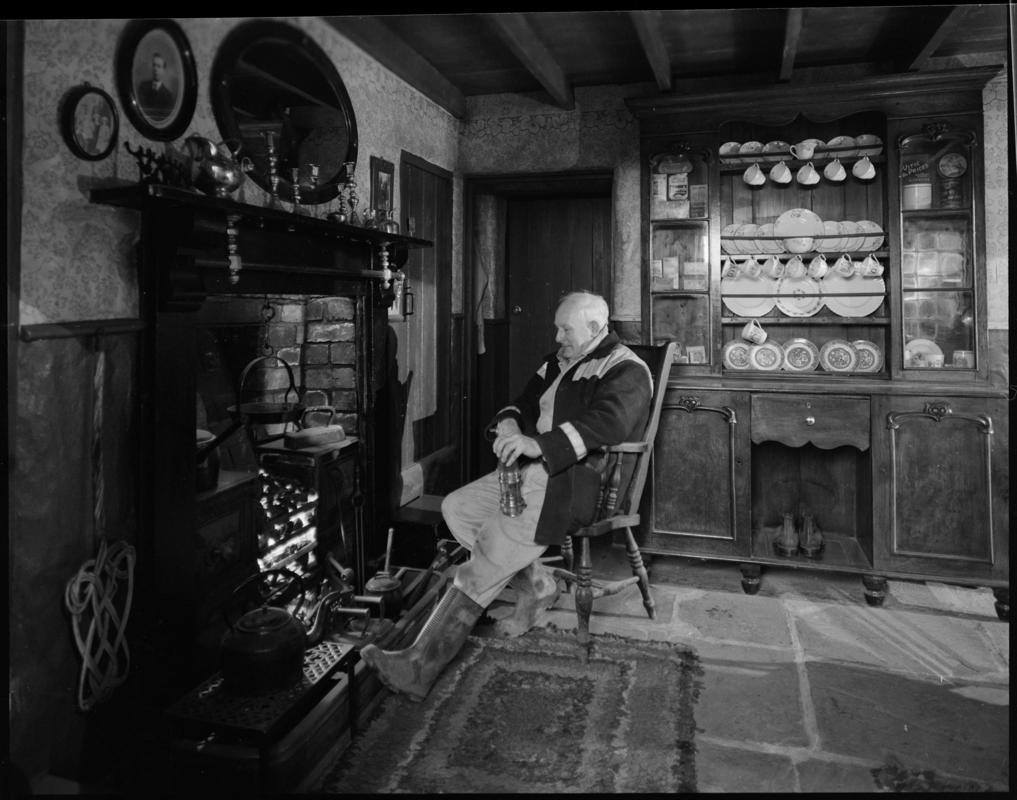 Black and white film negative showing a man inside a cottage, Blaenavon.