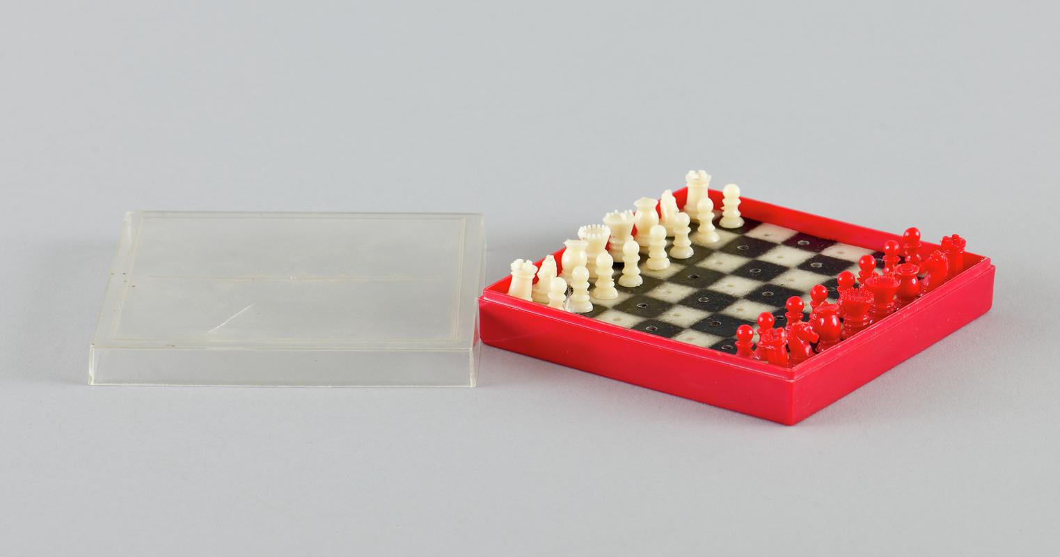 Mini plastic travel chess set. Red base with clear plastic top.