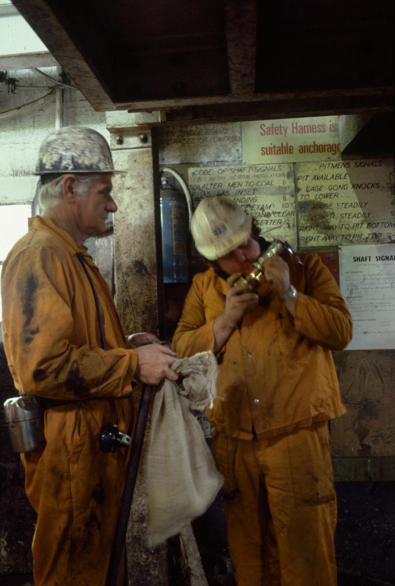 Colour film slide showing two miners checking lamps at pit bank, Oakdale Colliery 21 May 1981.
