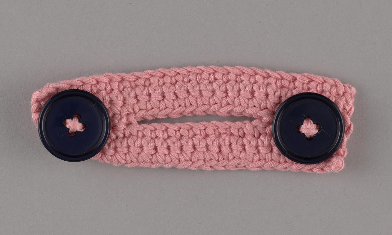 Hand-knitted ear protector/mask extender. Pink with purple buttons.
