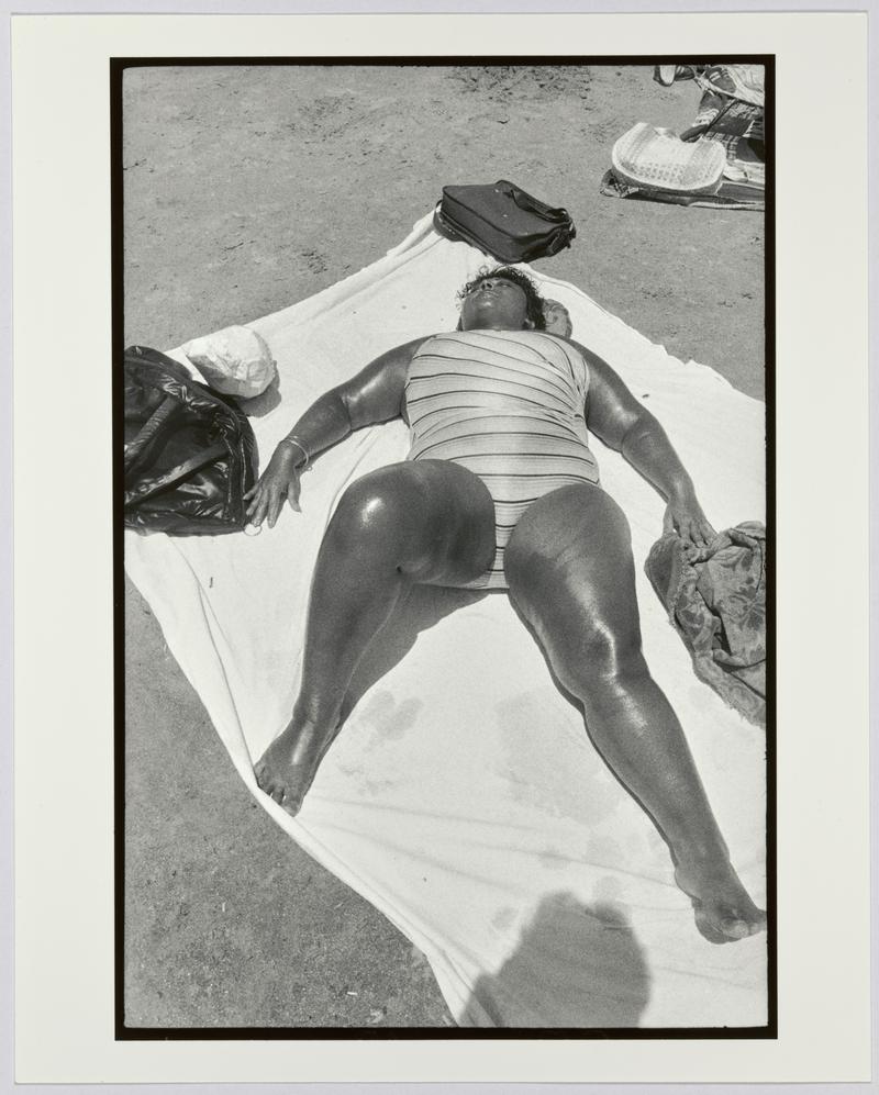 An overweight woman sunbathes on the beach, Coney Island, NYC