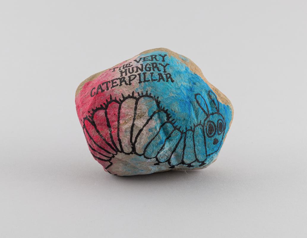 Stone painted with image of a caterpillar with inscription &#039;THE VERY / HUNGRY / CATERPILLAR&#039; on the front