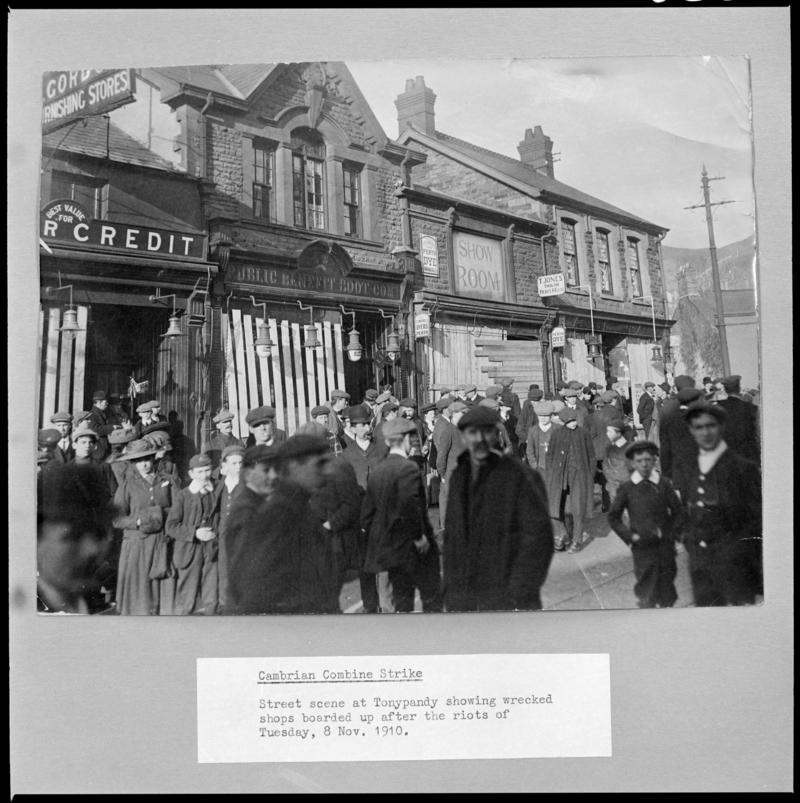 Black and white film negative of a photograph showing a street scene at Tonypandy.  Shops are boarded up after the riots of Tuesday 8 November 1910 (information taken from caption below the photograph).  &#039;Cambrian Strike 1910&#039; is transcribed from original negative bag.