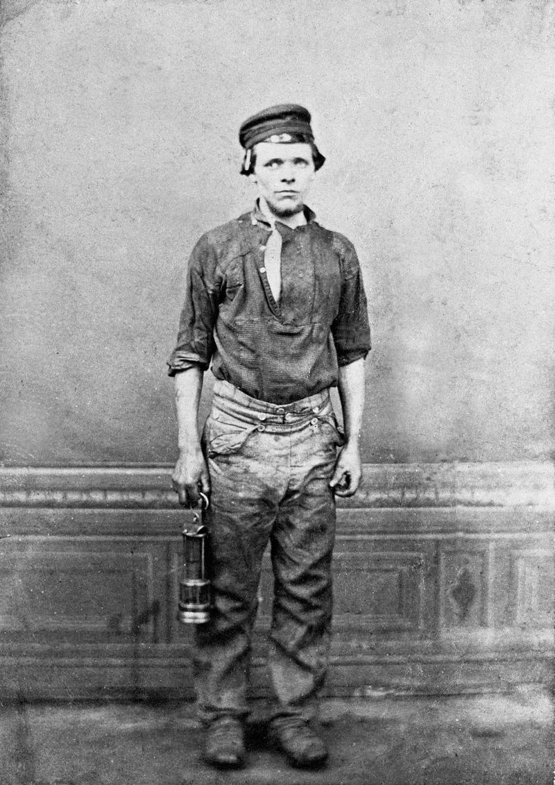 Colliery worker holding a miner&#039;s lamp in right hand.