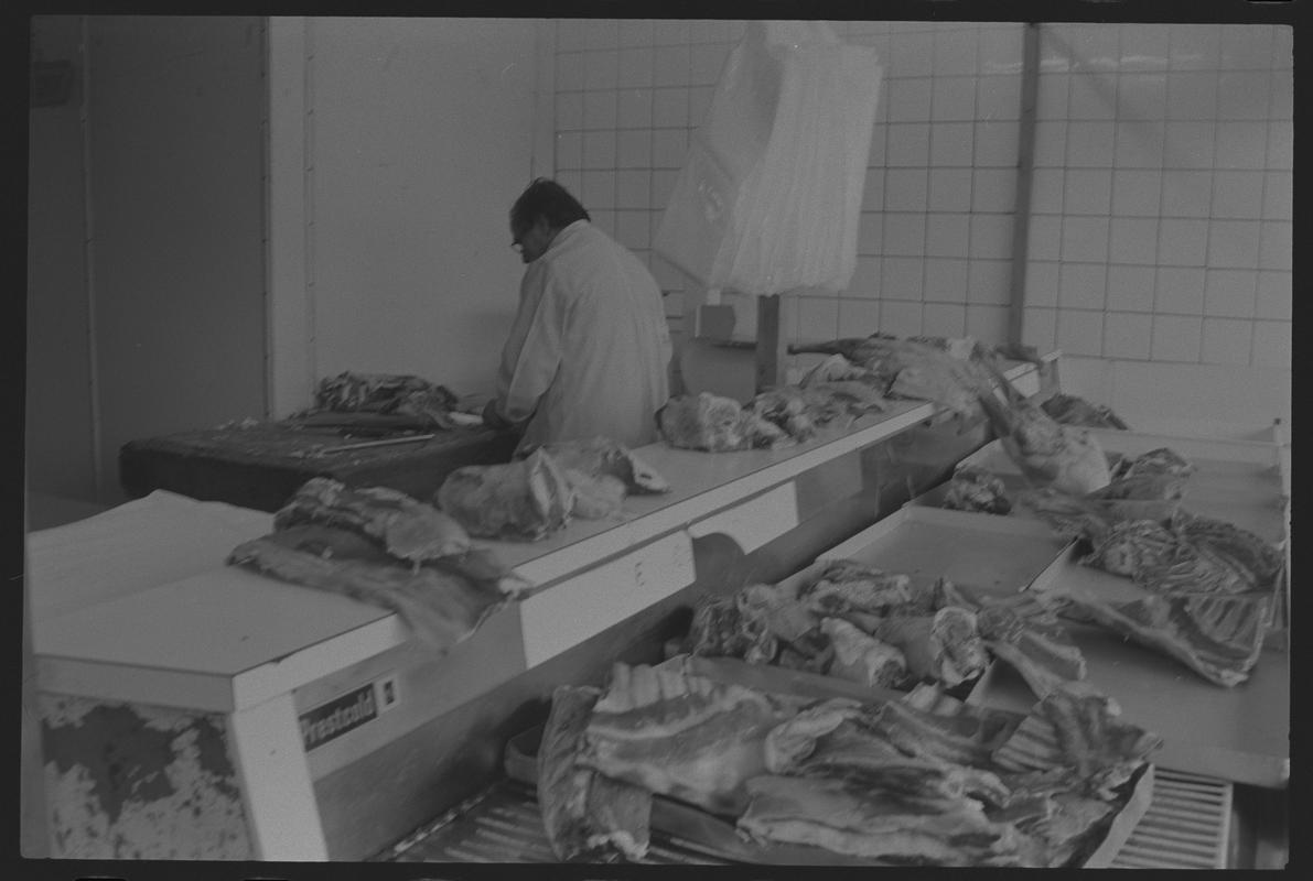 Butcher with meat ready for preparation in shop, Loudoun Square, Butetown.