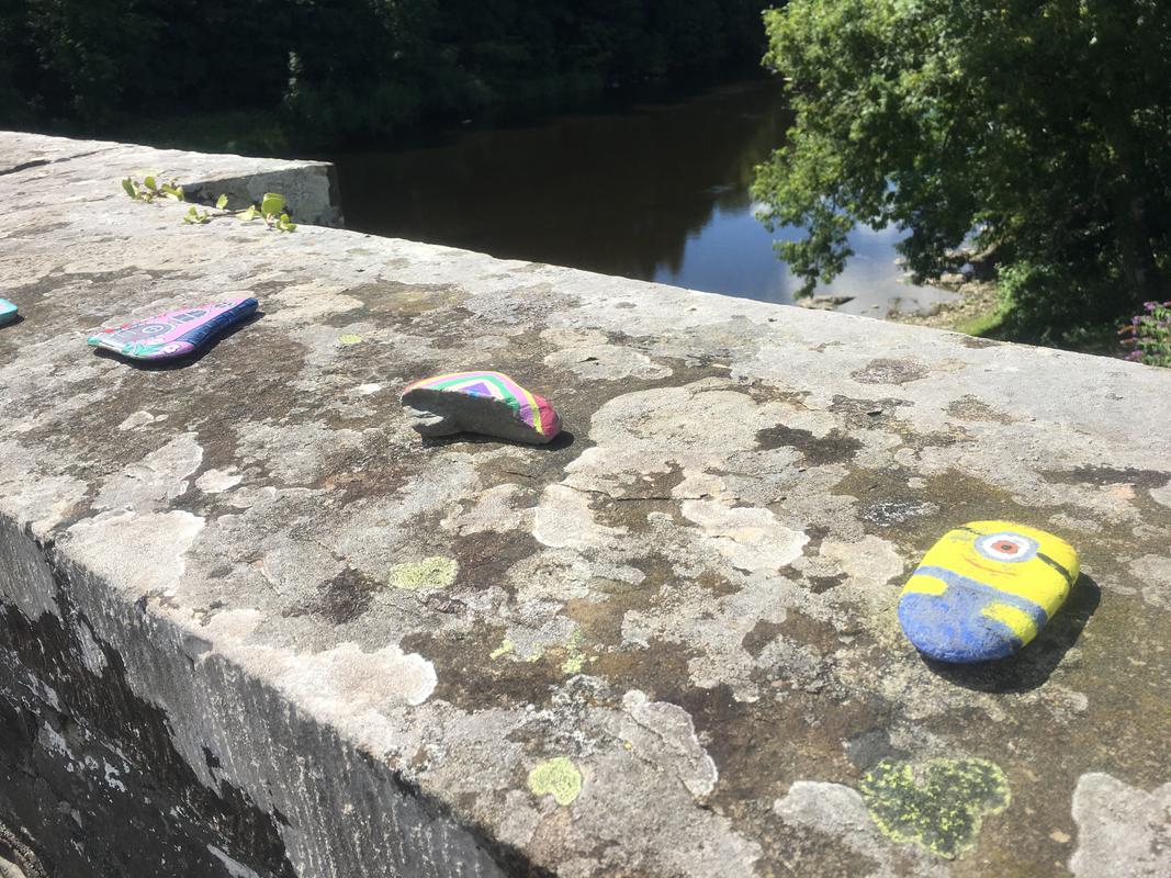 Pebbles painted with a Minion, a rainbow and a fairy door on Boughrood Bridge, over the River Wye, Boughrood,Powys.