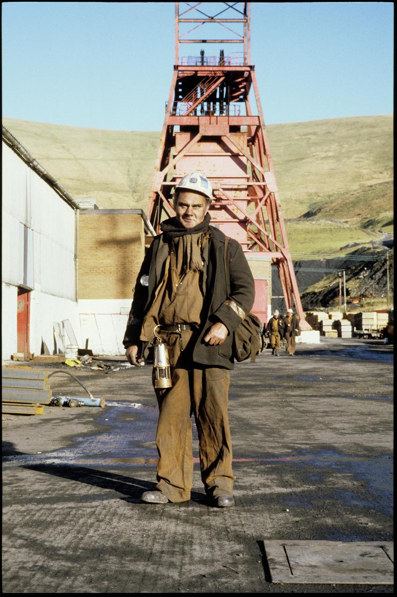 Colour film slide showing a miner with the upcast shaft in the background, Ocean Colliery.