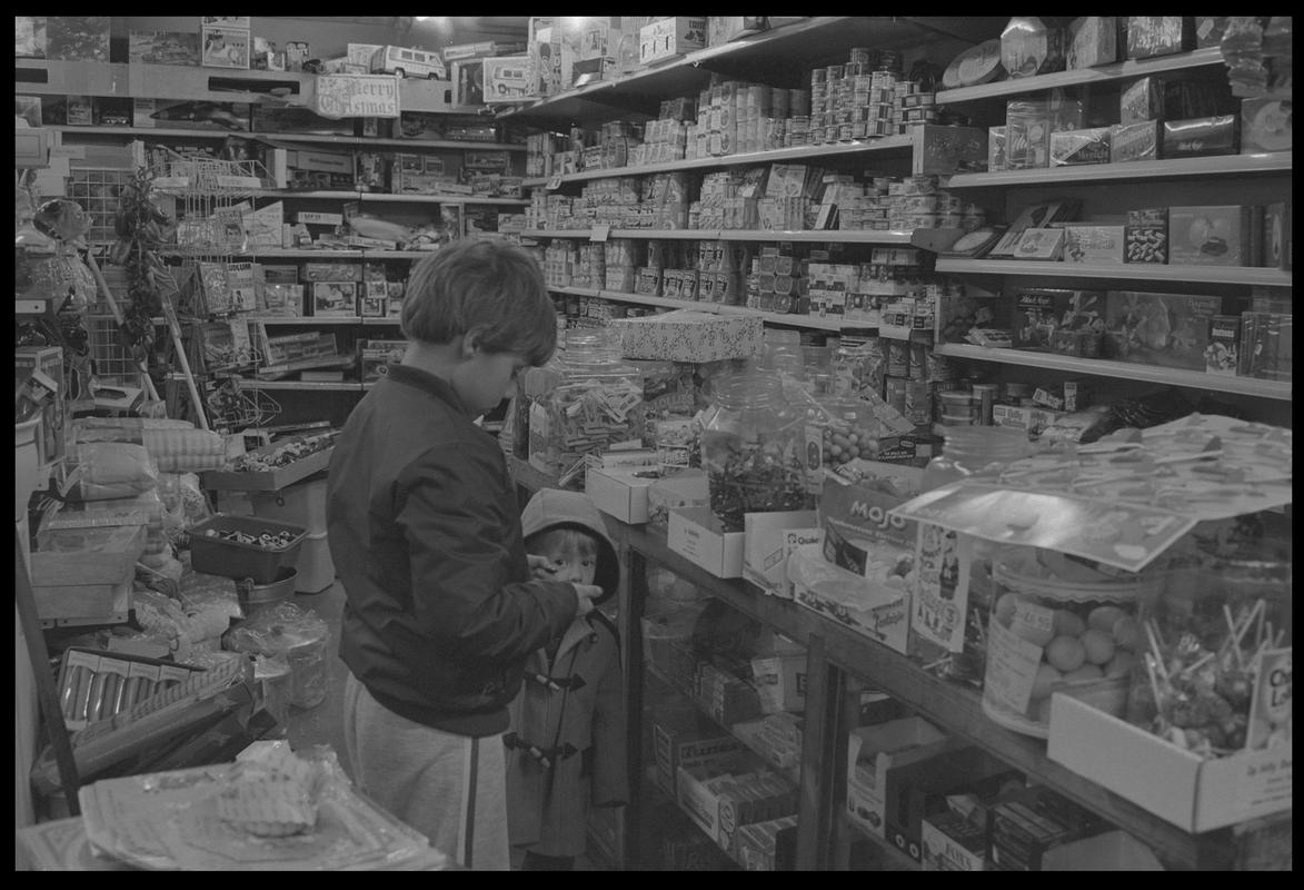 Child at counter in newsagents, Loudoun Square, Butetown.