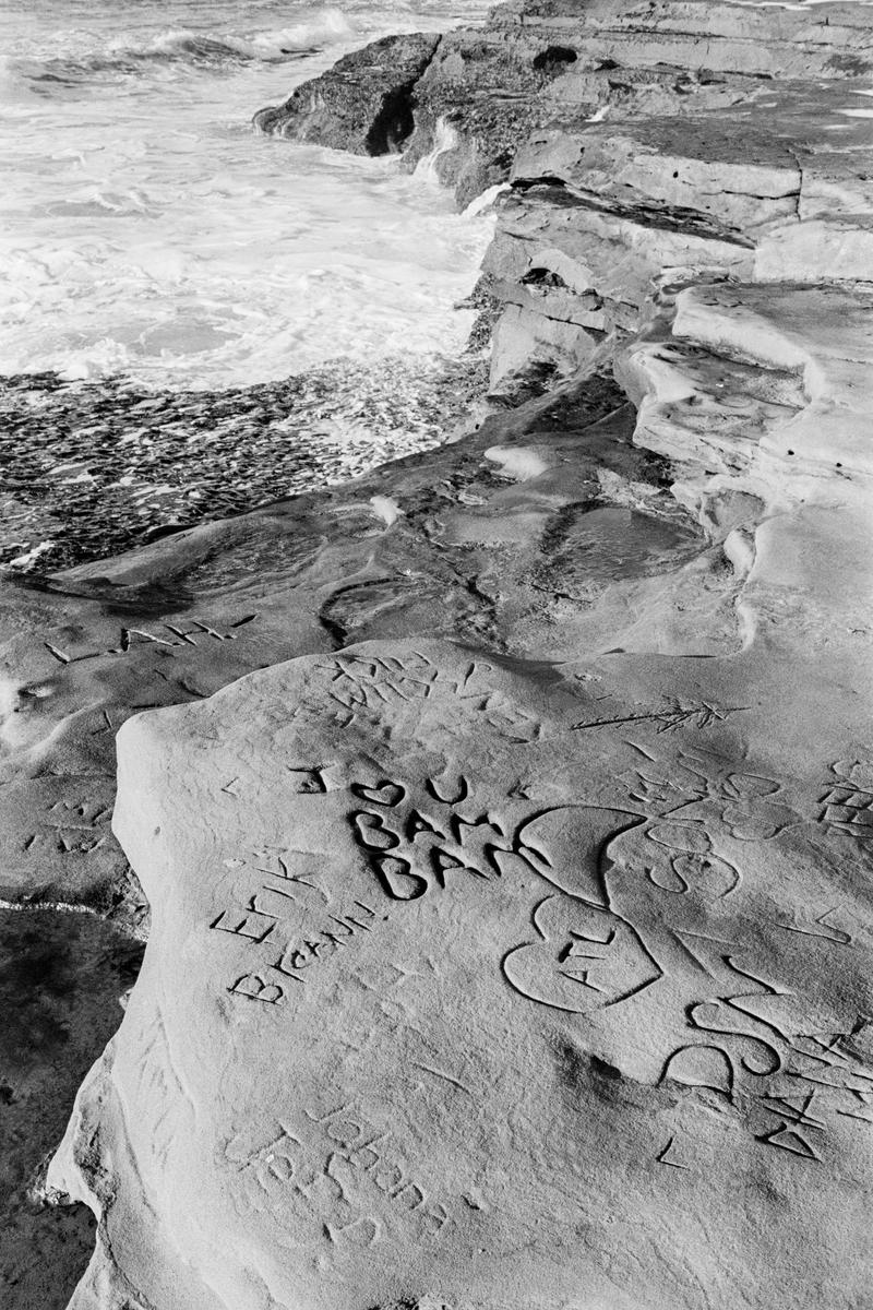 USA. CALIFORNIA. San Diego, Misson Beach, Grafitti carvings on beach rocks. 2006.