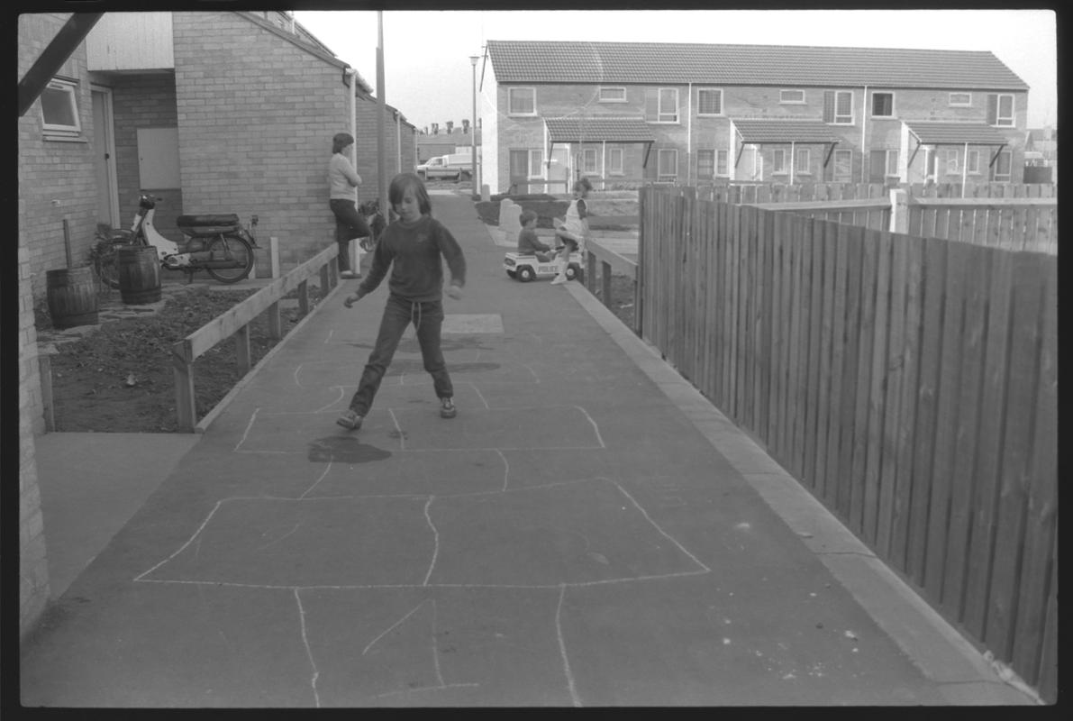 Child playing hopscotch in front of new houses at Eleanor Place, Butetown.