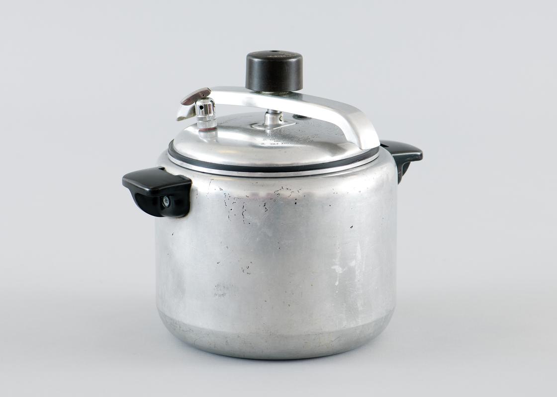 Aluminium pressure cooker. Inside there are three vegetable steamers, a complete set. Operational instructions stamped on lid.  (See 2011.60/68 for instructions)