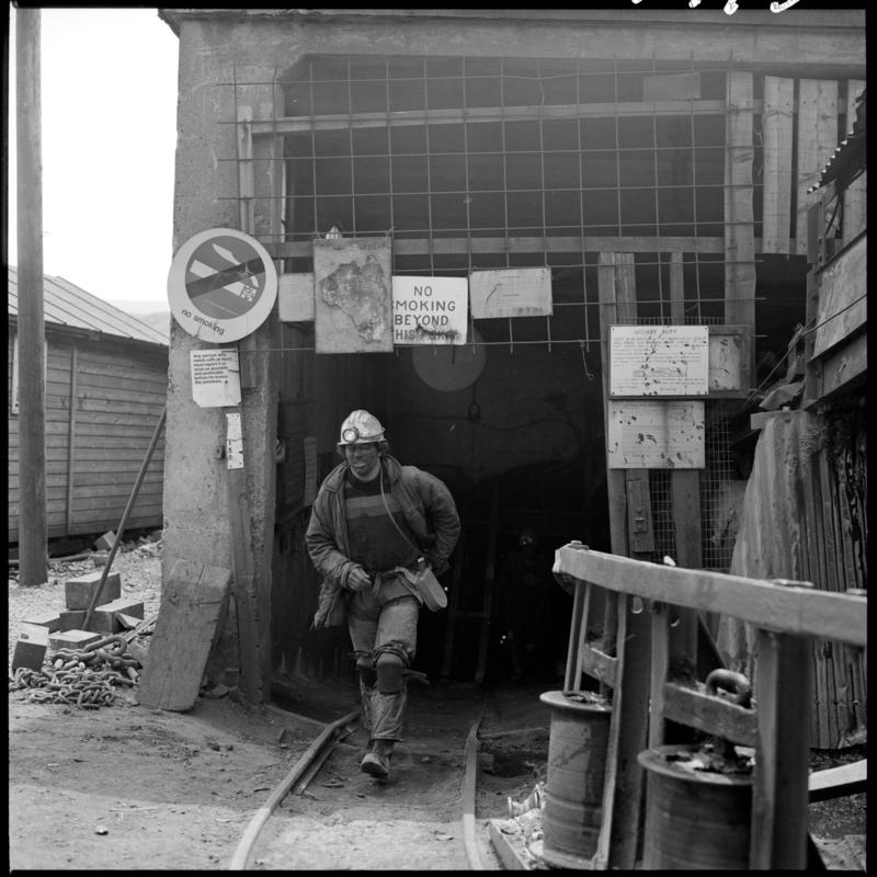 Black and white film negative showing a mainer arriving back on the surface after his shift, Big Pit 1979.