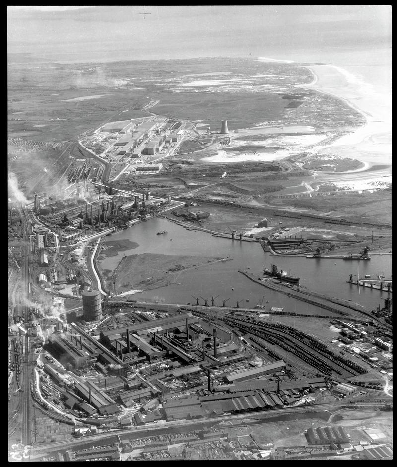 Aerial view across Port Talbot docks showing full views of Port Talbot Steelworks (nearest camera), Margam Steelworks, and the new Abbey Steelworks in the distance.